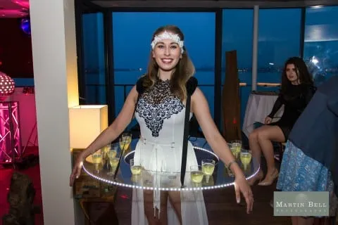 Hostess wearing an illuminated LED strolling table serving champagne