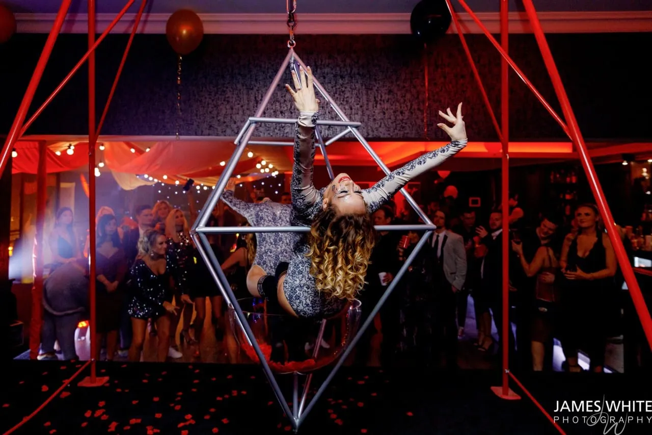 Aerialist in leopard print performing on a prism frame at a twisted circus party